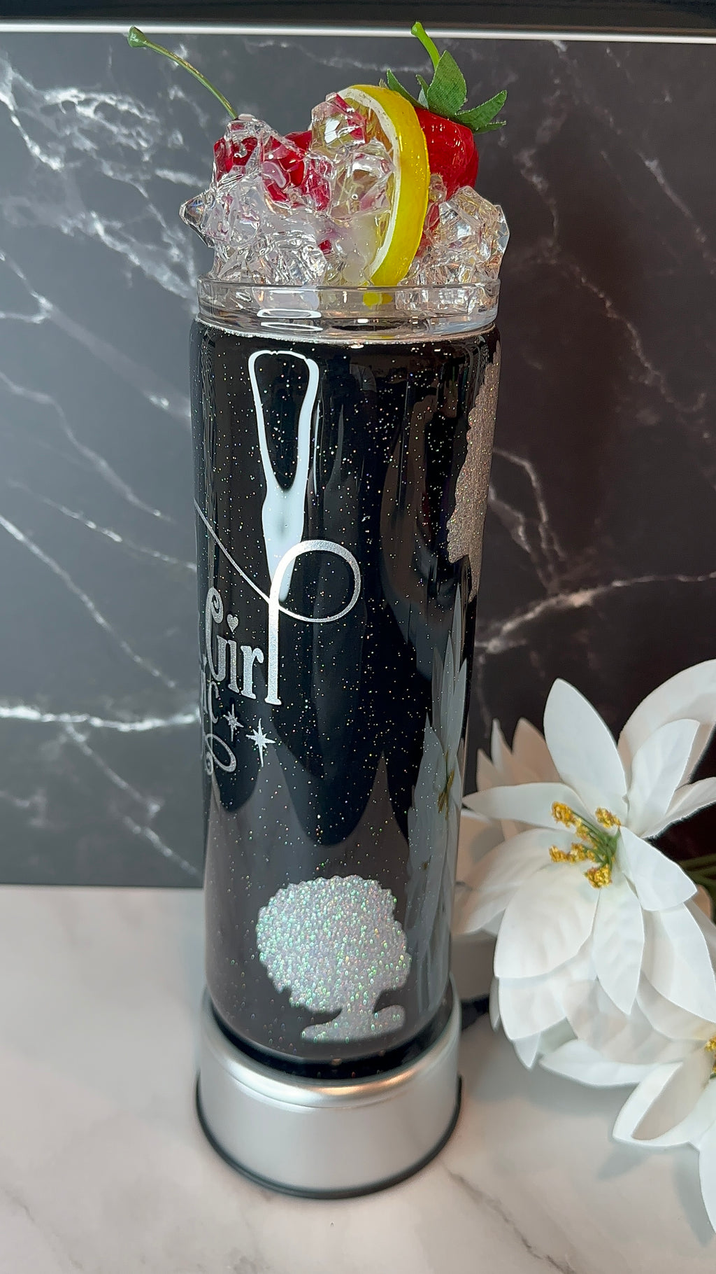 Black cocktail shaker with ice, lemon, and berries on a marble surface.